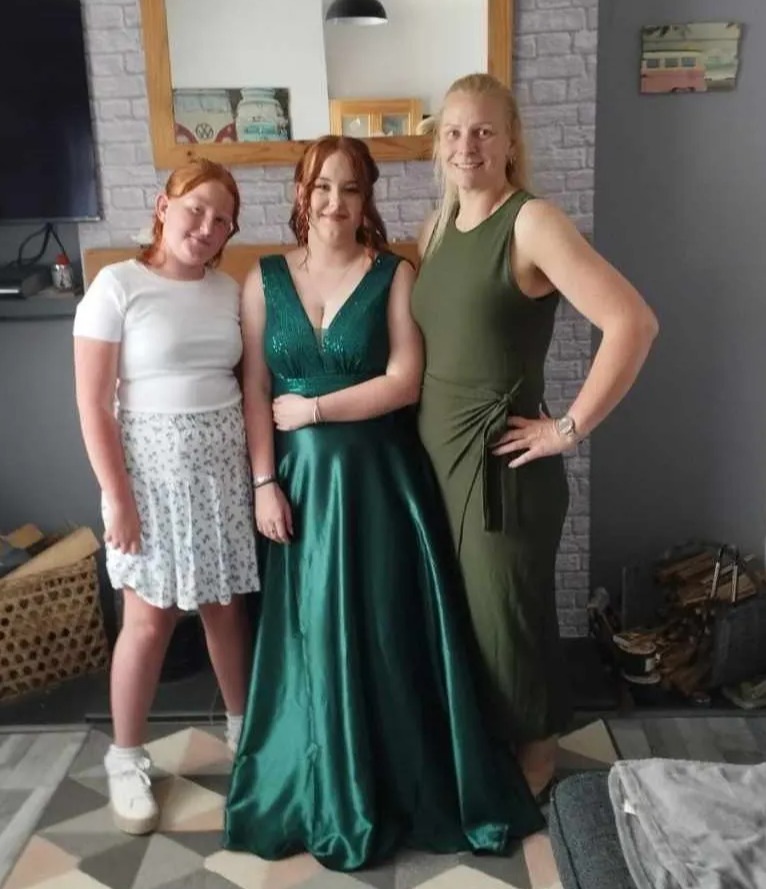 a woman in a green dress stands next to two other women