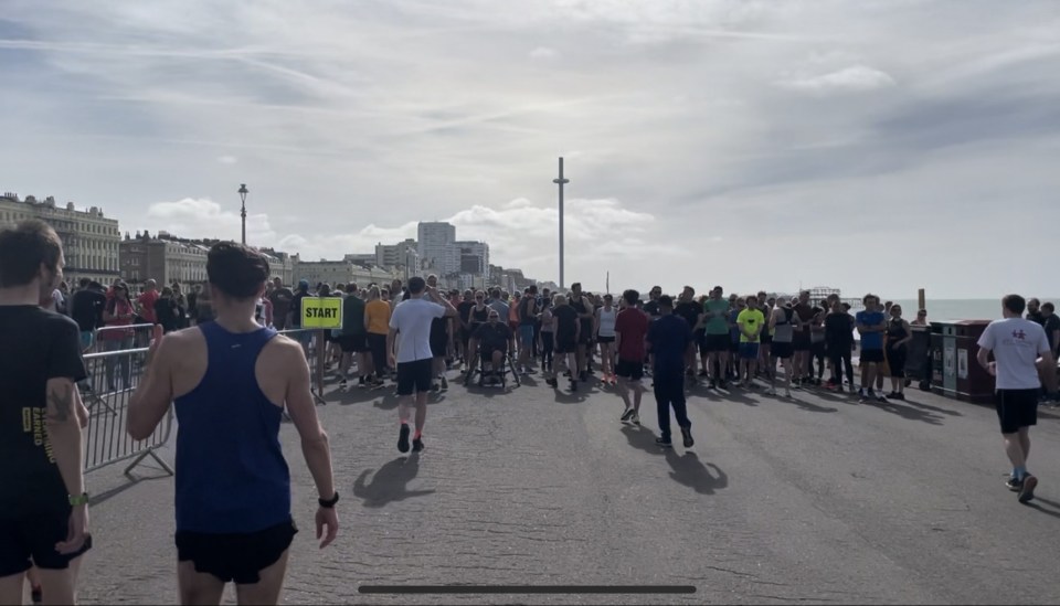 a large group of people are gathered on a street with a yellow sign that says start