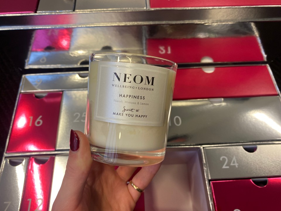 a person holding a candle that says neom on it