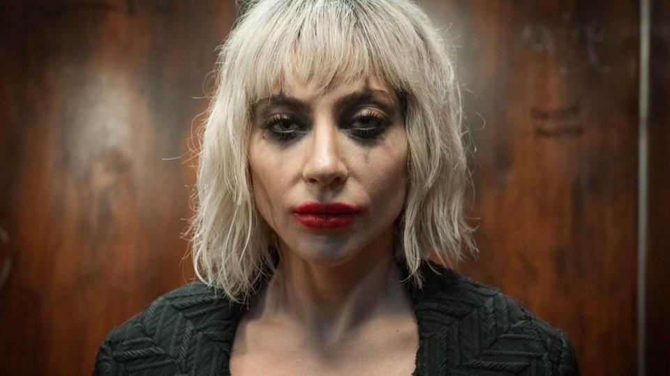 a woman with blonde hair and red lips is wearing a black jacket