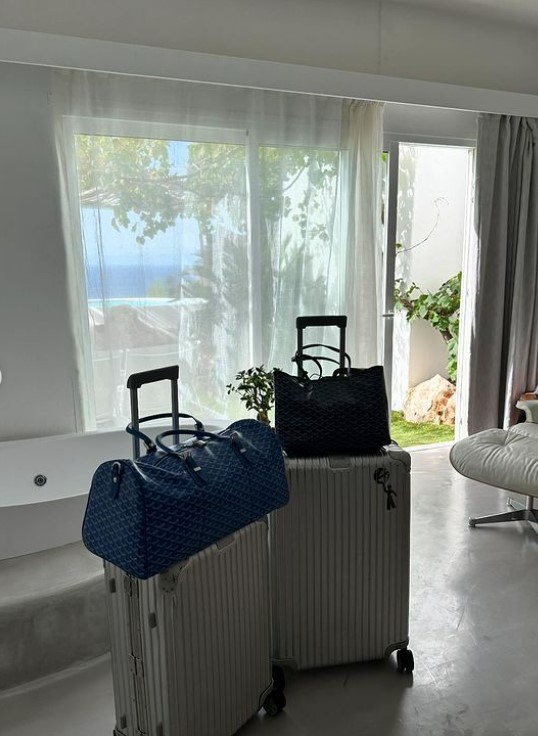 two suitcases and a bag in a room with a view of the ocean