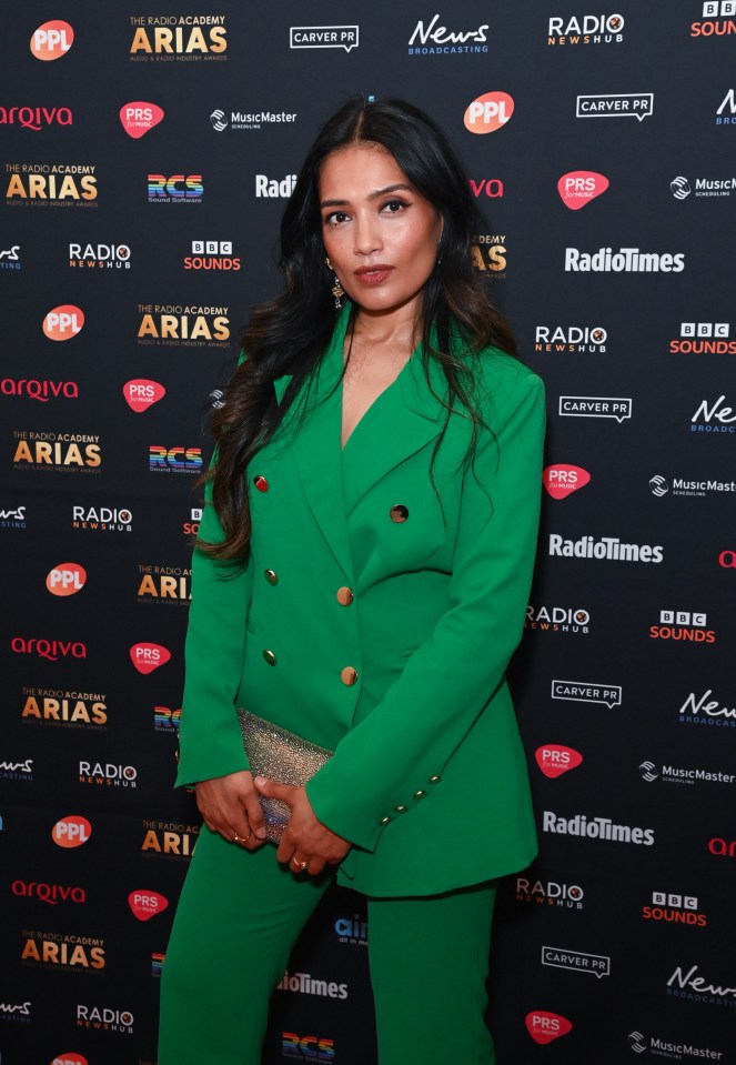 a woman in a green suit stands in front of a wall that says radiotimes