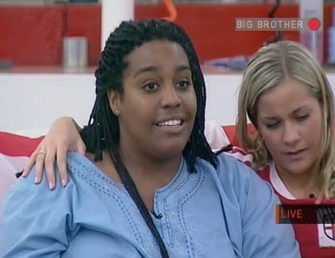 two women are sitting on a couch and one of them is wearing a big brother shirt