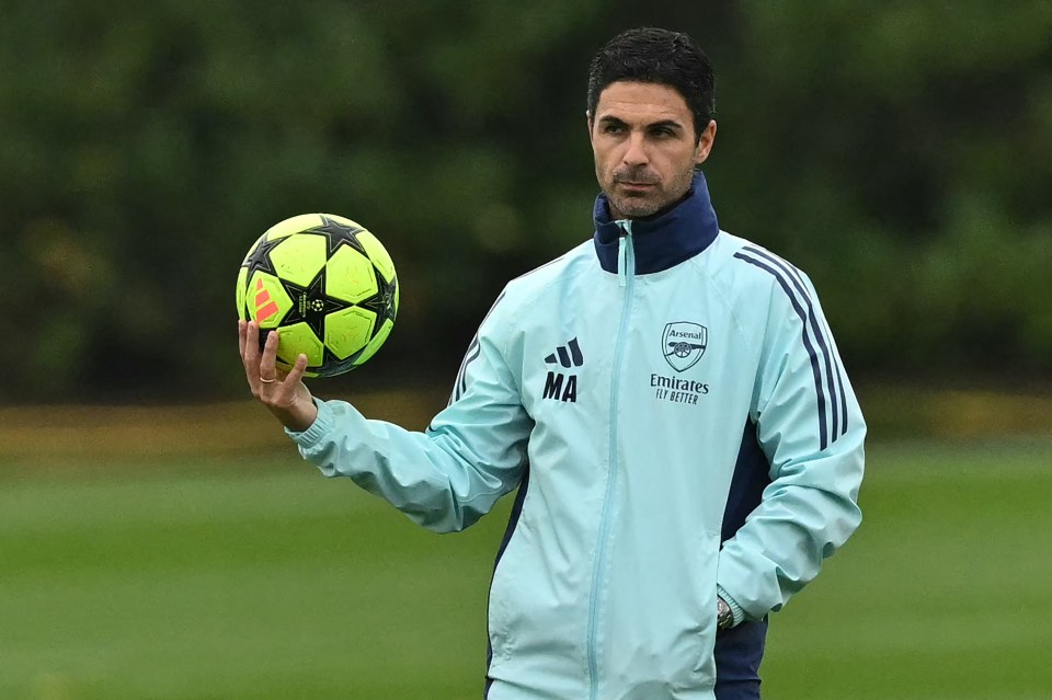 a man in an arsenal jacket holds a soccer ball