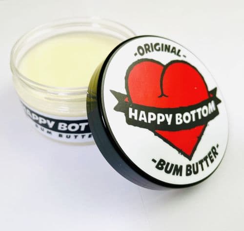 a jar of happy bottom bum butter with the lid open on a white surface .