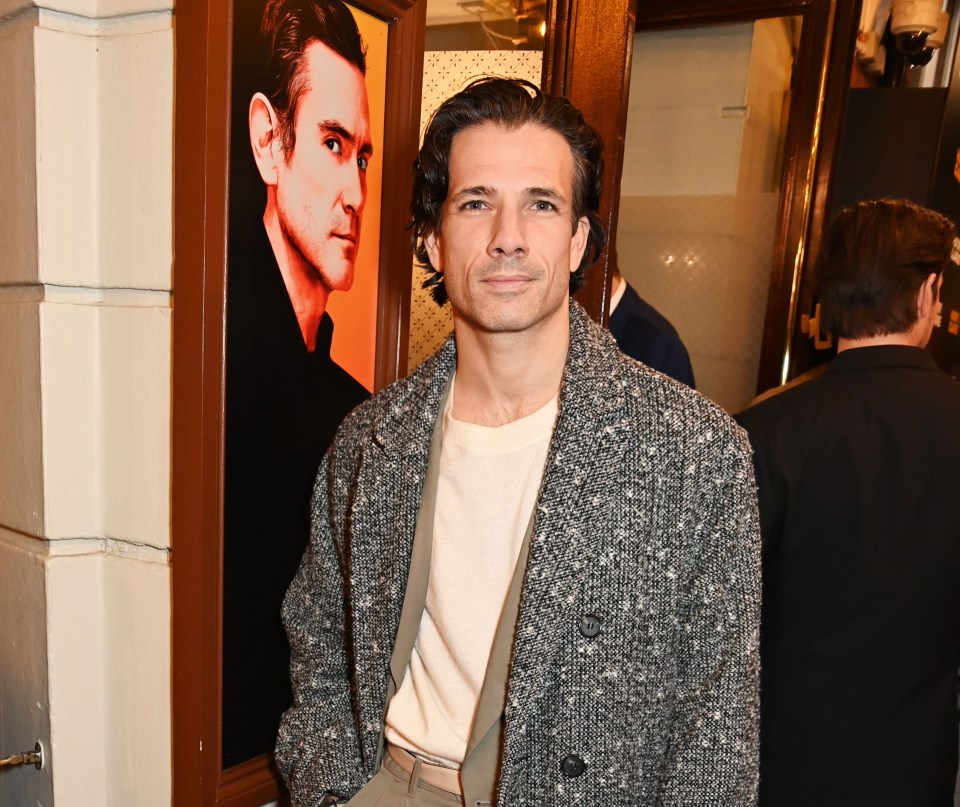a man standing on a red carpet with his hands in his pockets