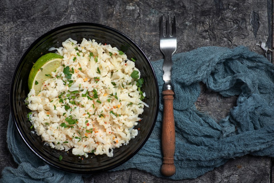 a bowl of rice with a lime wedge and a fork