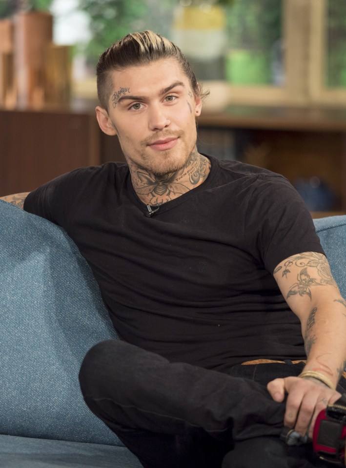 a man with a tattoo on his face is sitting on a couch