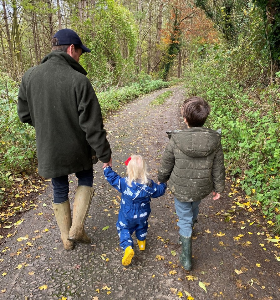 a man and two children are walking down a path holding hands