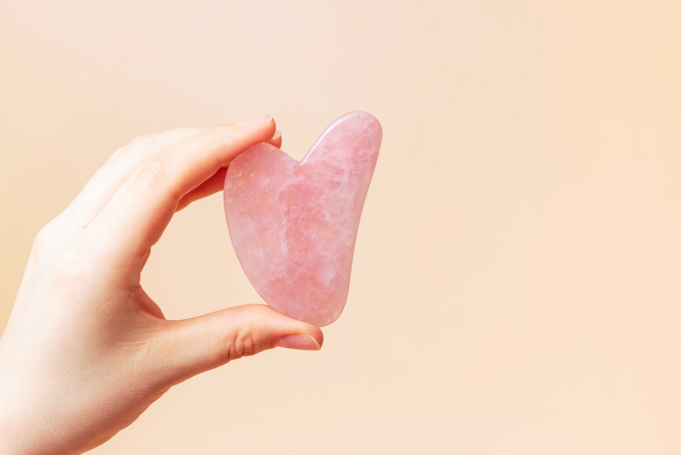a hand is holding a pink heart shaped object