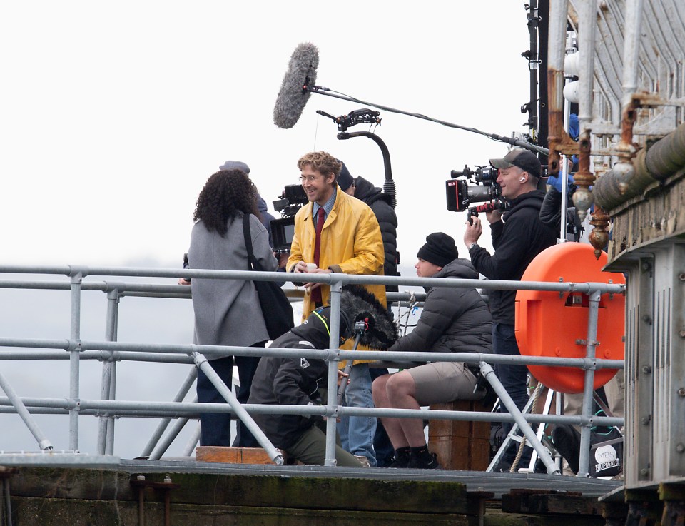 a man in a yellow jacket is being filmed by a group of people