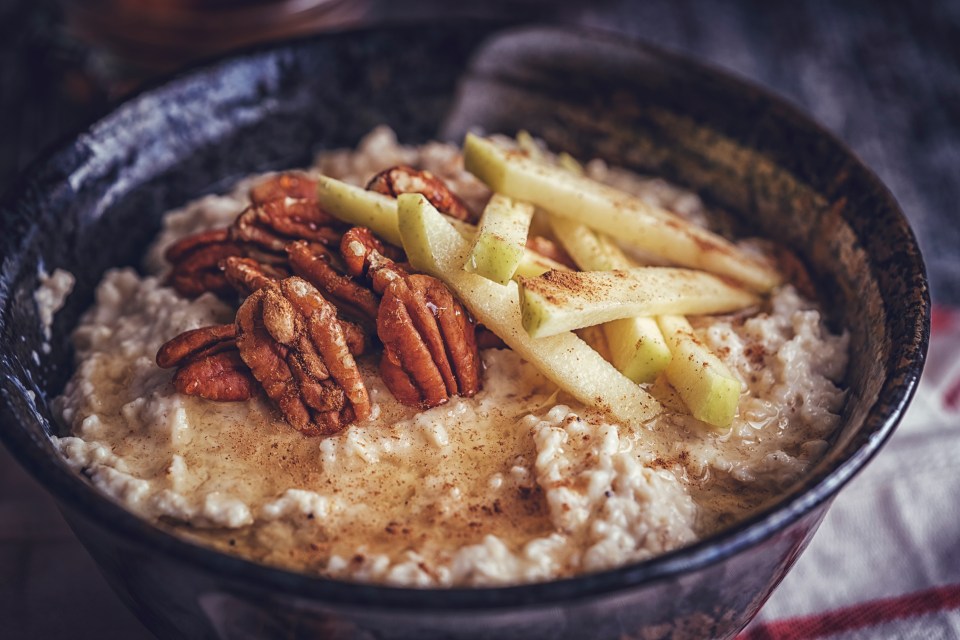 a bowl of oatmeal with apples and pecans on top