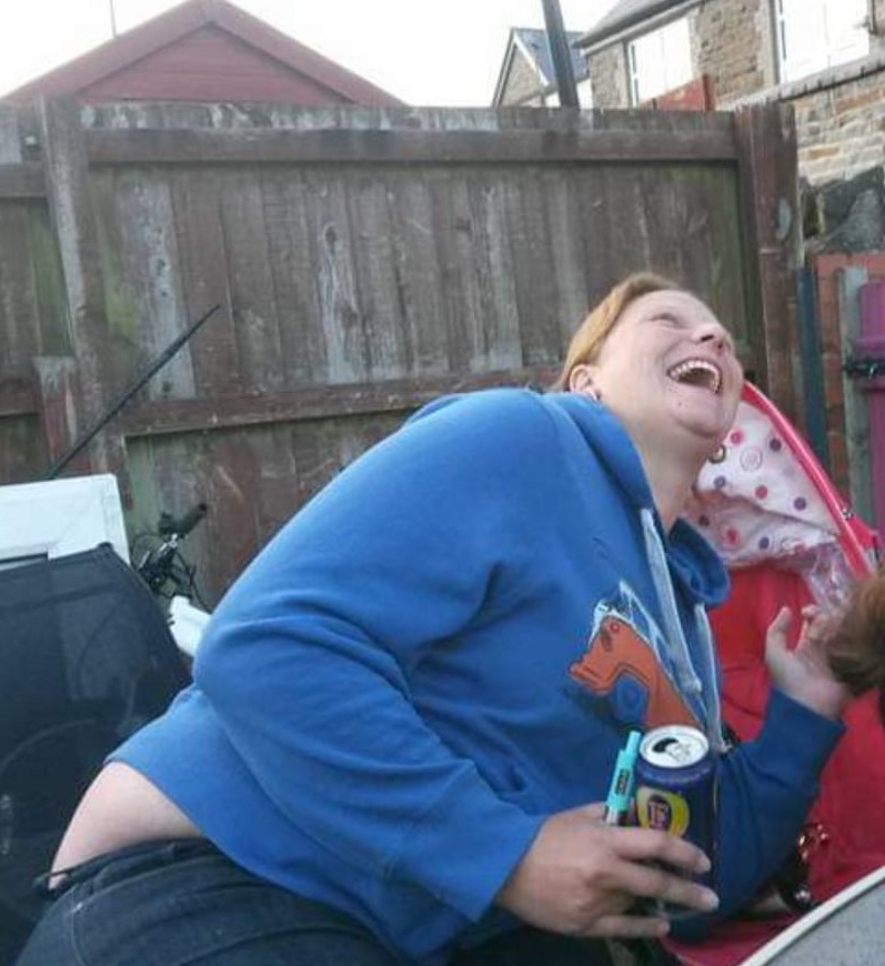 a woman in a blue sweatshirt is holding a can of pepsi and laughing .