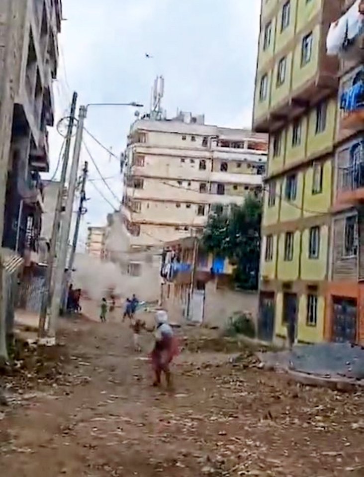 a group of people are walking down a dirt road in a city .