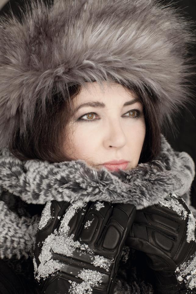 a woman wearing a fur hat and gloves covered in snow