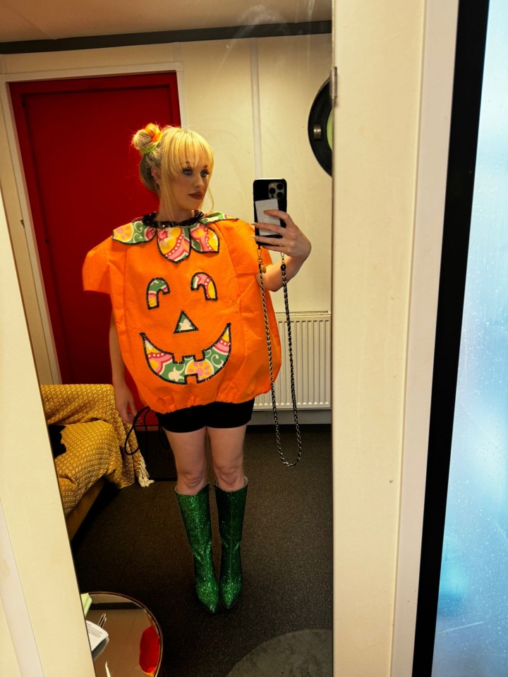 a woman in a pumpkin costume takes a selfie in a mirror