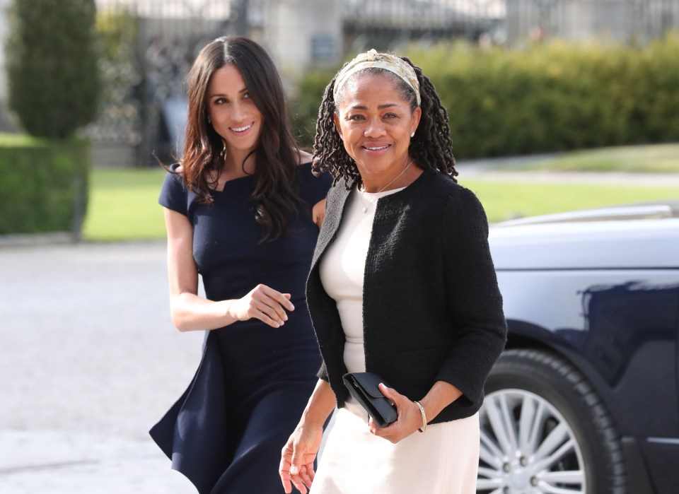 a woman in a black jacket stands next to another woman in a white dress