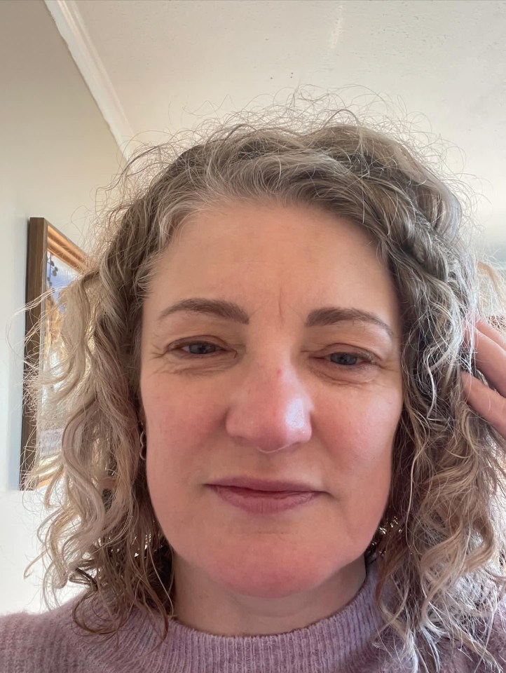 a woman with curly hair is wearing a purple sweater