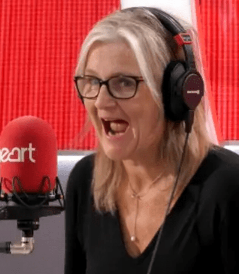a woman wearing glasses and headphones is singing into a microphone .
