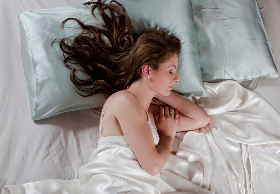 a woman is sleeping on a bed with two pillows