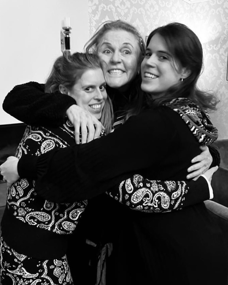 three women hugging each other with one wearing a paisley shirt
