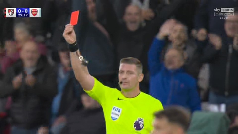 a referee is holding up a red card during a soccer game .
