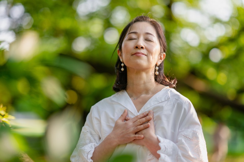 a woman with her eyes closed and her hands on her chest
