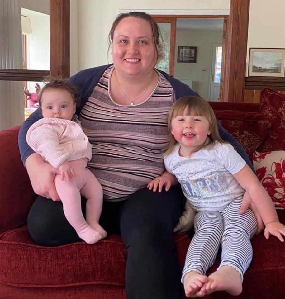 a woman sits on a couch with two children one of whom is wearing a shirt that says happy