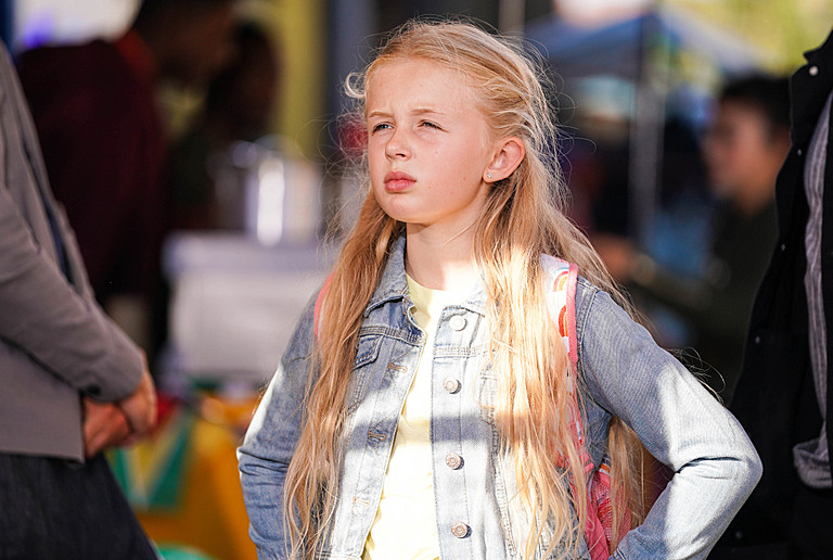 a little girl with long blonde hair wearing a denim jacket