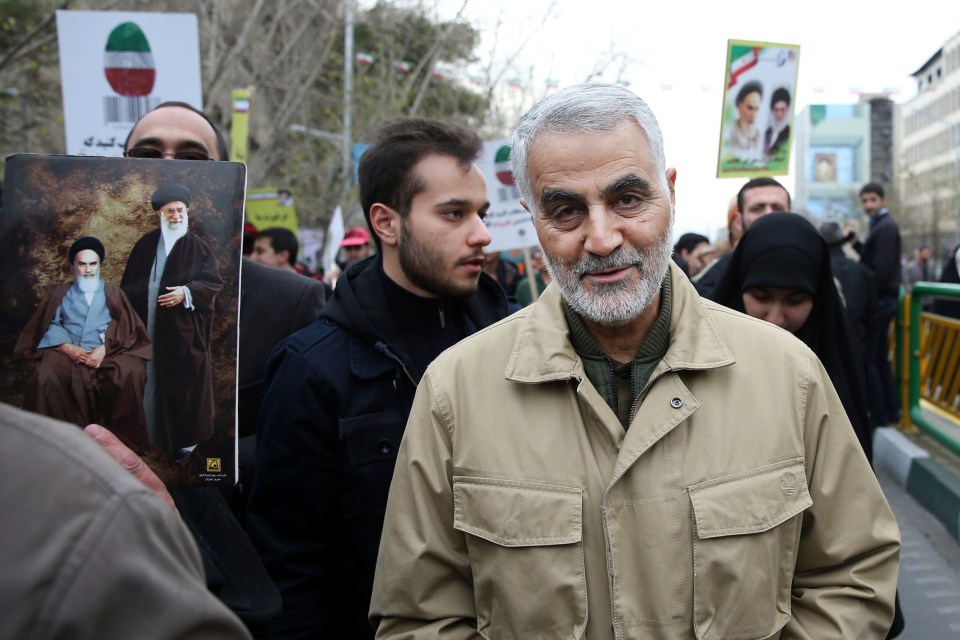 a man in a tan jacket holds a picture of a man with a beard