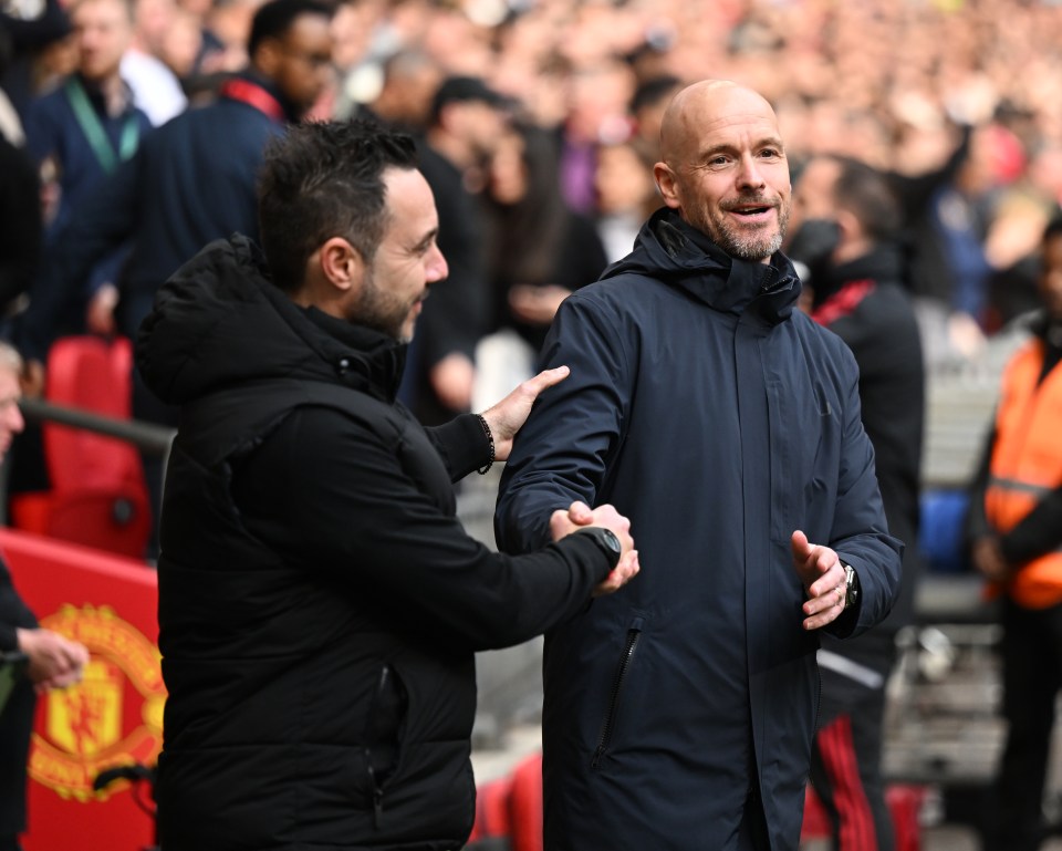 two men shake hands in front of a manchester united banner