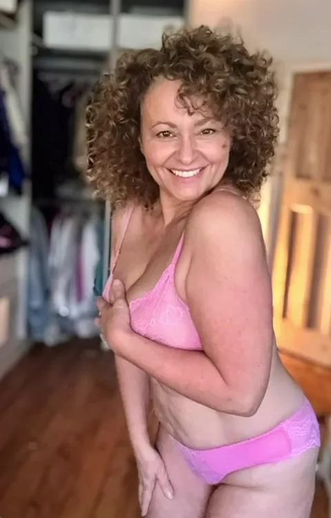 a woman with curly hair is wearing a pink bra and panties