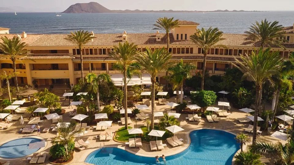 an aerial view of a resort with a large pool and palm trees