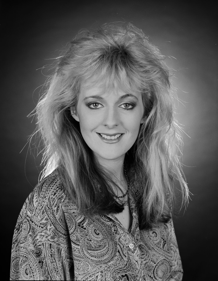 a woman in a paisley shirt smiles for the camera