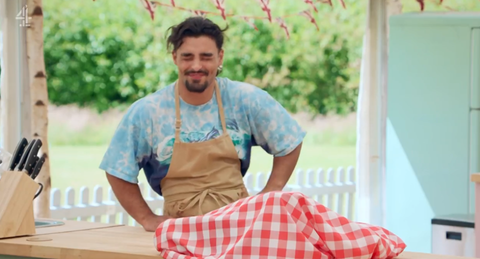 a man in an apron stands behind a checkered table cloth