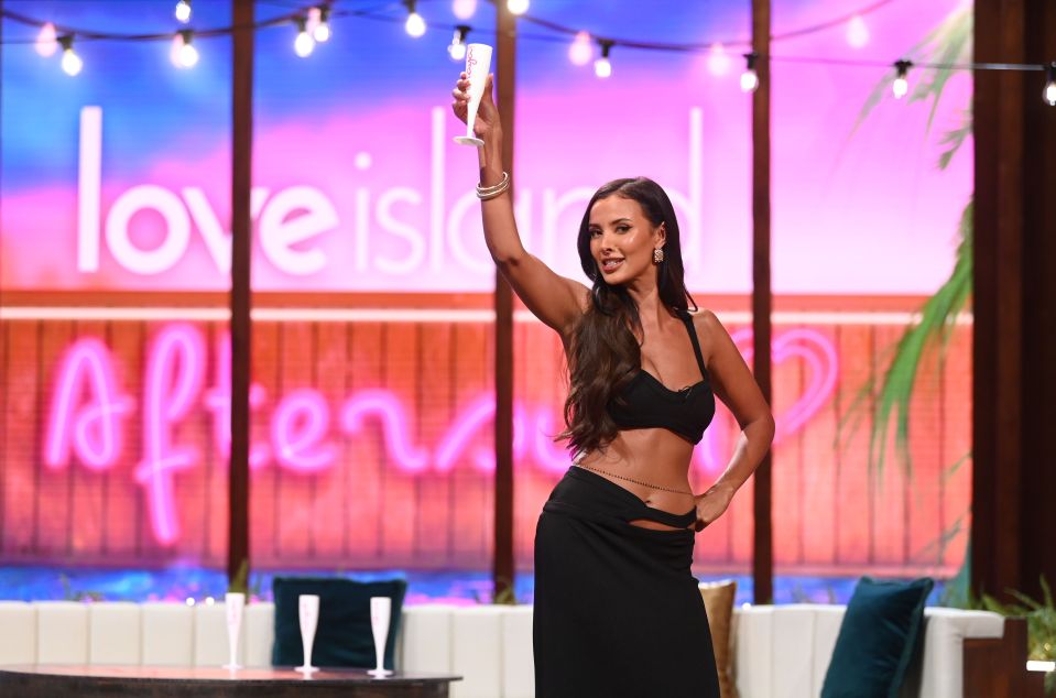 a woman stands in front of a love island sign
