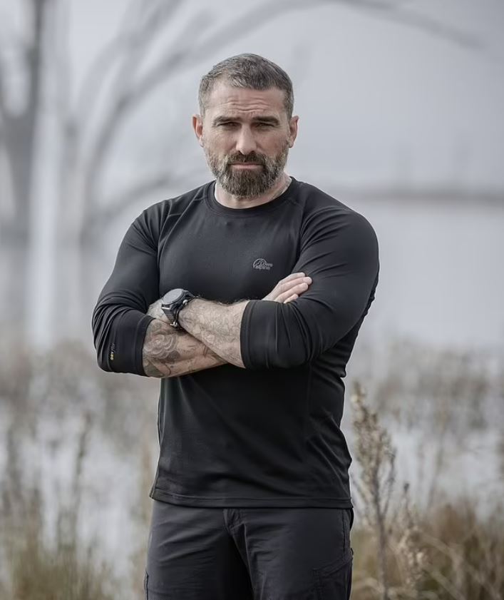 a man with his arms crossed wearing a lowa shirt