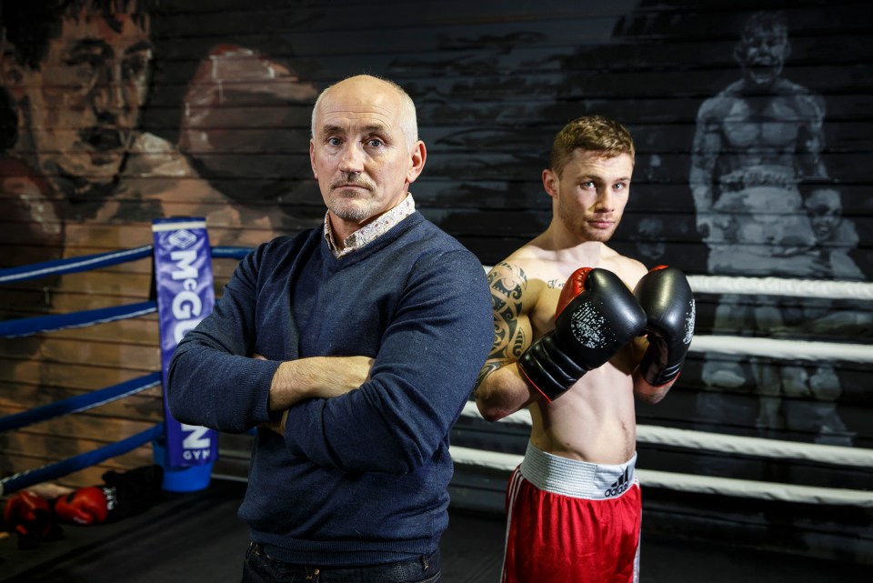 a man in a blue sweater stands next to a man in boxing gloves