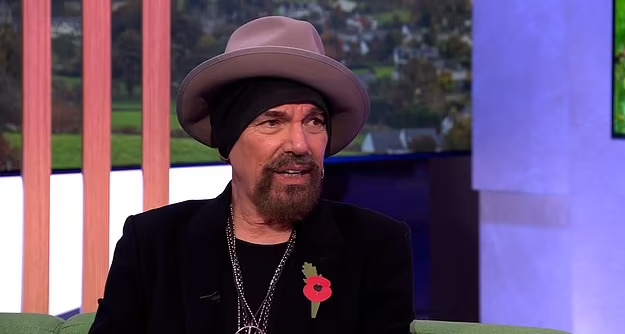 a man with a beard and a hat is sitting on a couch .