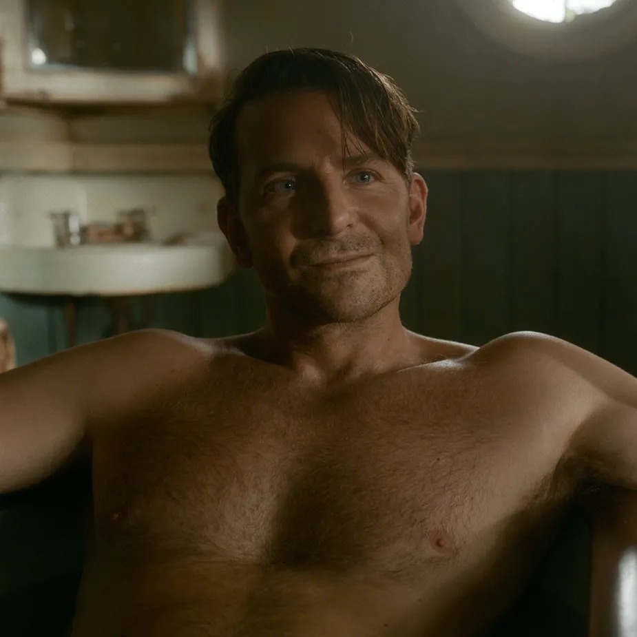 a shirtless man is sitting in a bathtub and smiling