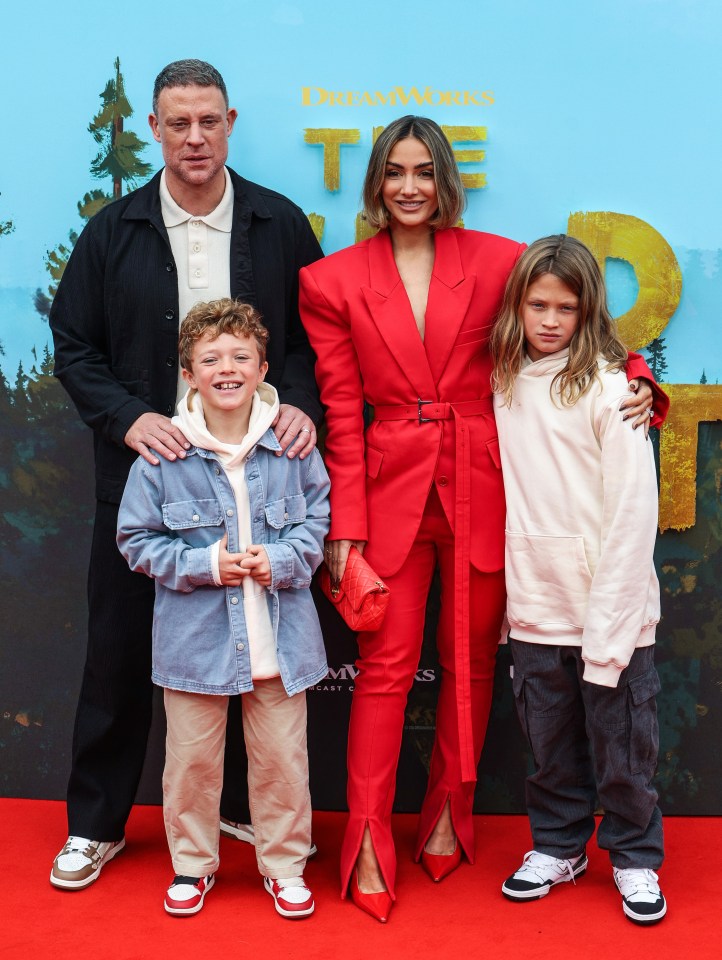 a family poses on a red carpet in front of a dreamworks sign