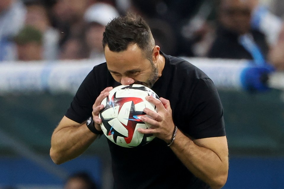 a man in a black shirt is kissing a soccer ball