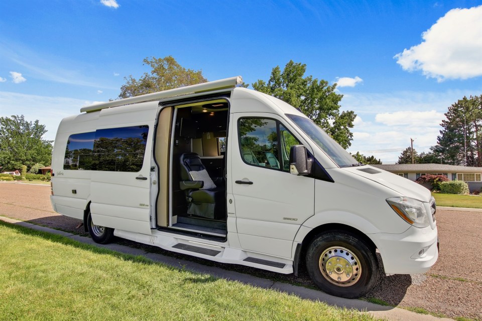a white van with the door open is parked on the side of the road