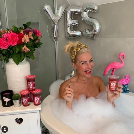 a woman is taking a bath and holding a cup of yogurt