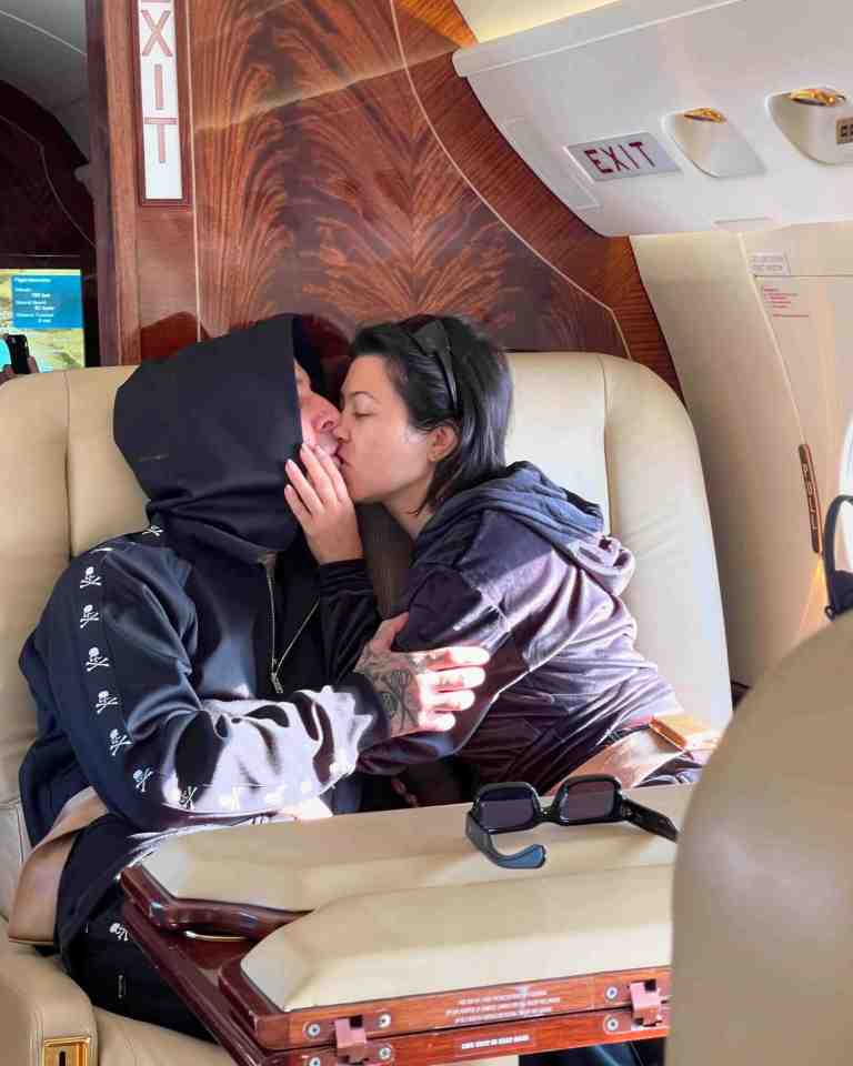 a man and woman are kissing in front of an exit sign