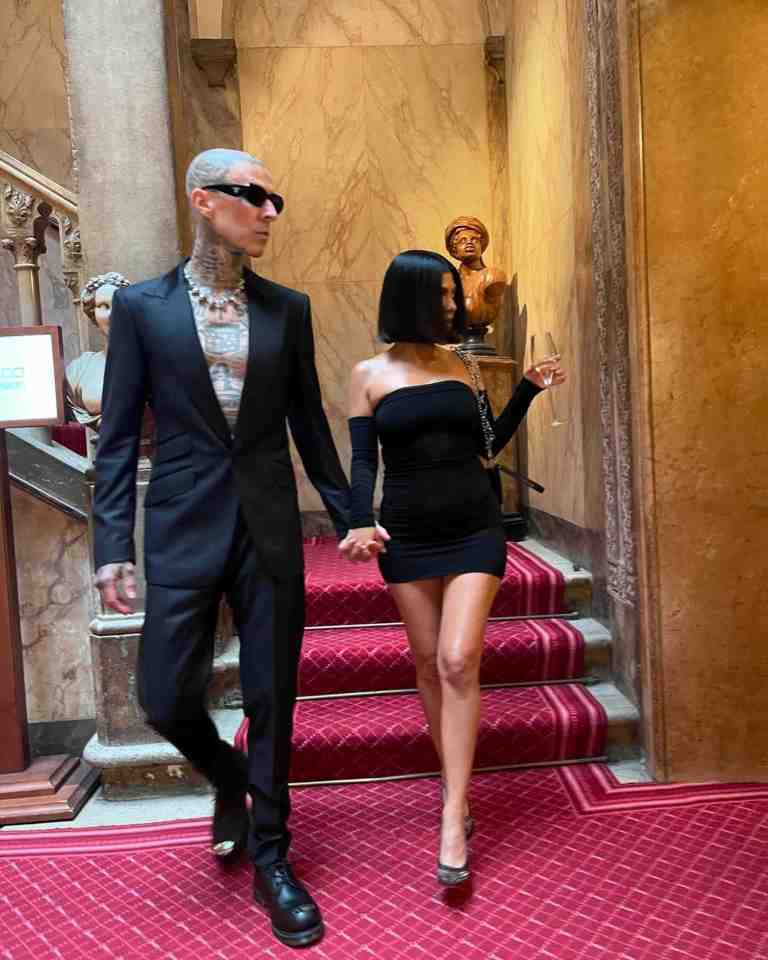 a man in a suit and a woman in a black dress are holding hands