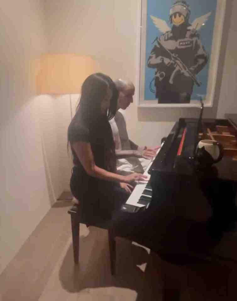 a man and a woman are playing a piano in front of a police poster