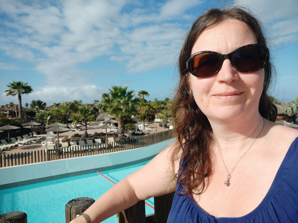 a woman wearing sunglasses stands in front of a pool