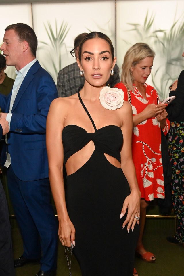 a woman in a black dress with a flower on her shoulder