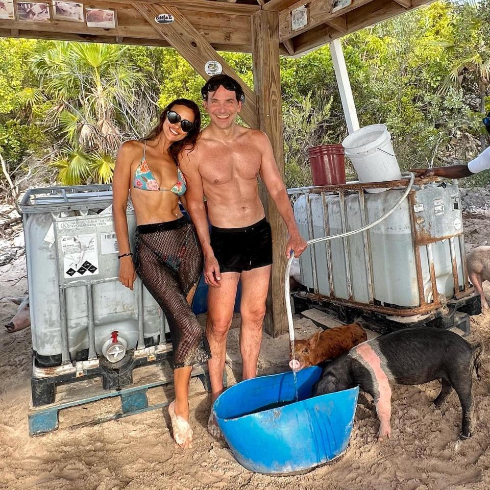 a man and a woman are standing next to pigs and a blue bucket